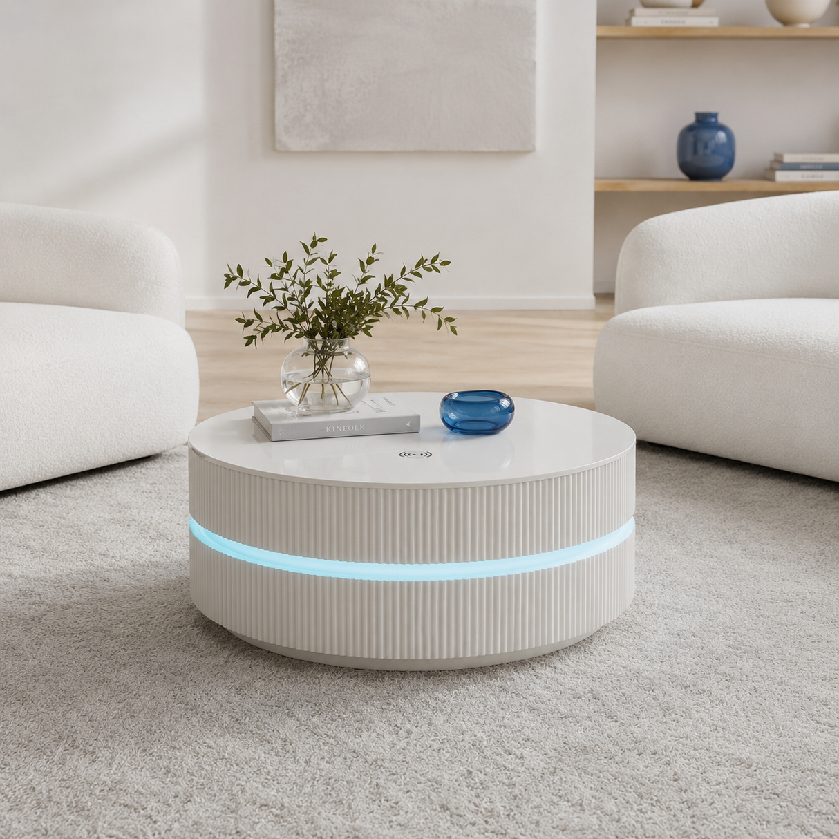 A modern round white coffee table with a ribbed lower section and a glowing blue LED light band, styled in a bright, minimalist living room with white armchairs and a light rug.