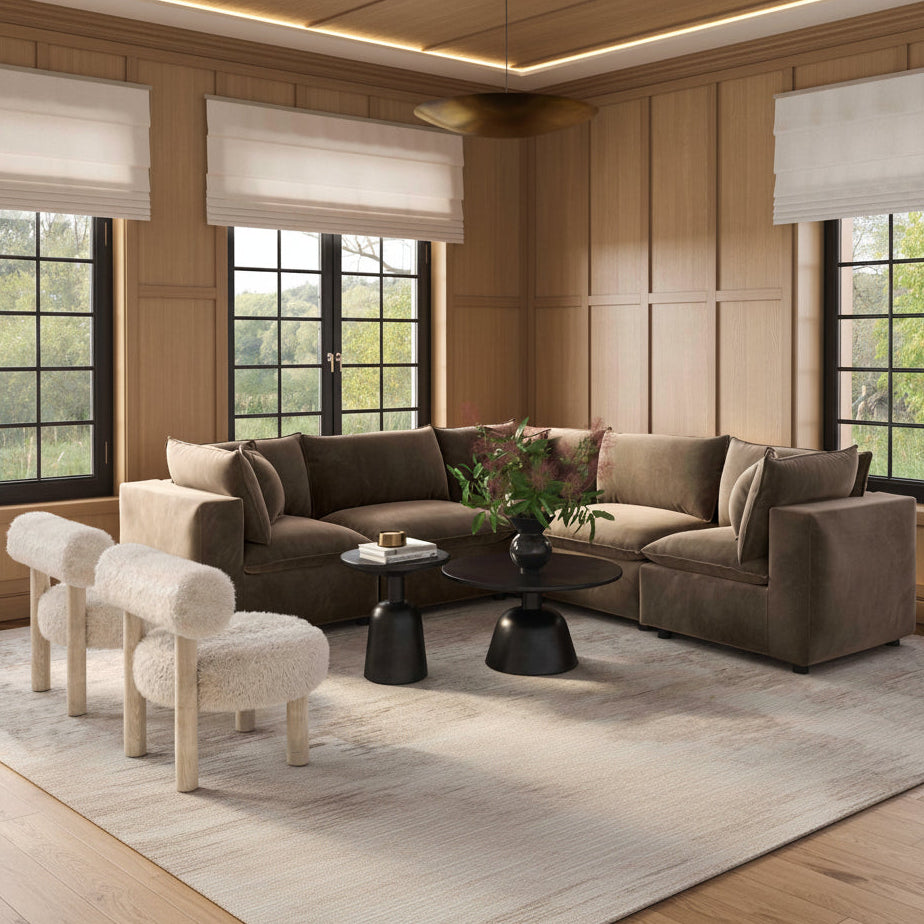 Modern living room with a brown sectional sofa, round black coffee table, and decorative plants.