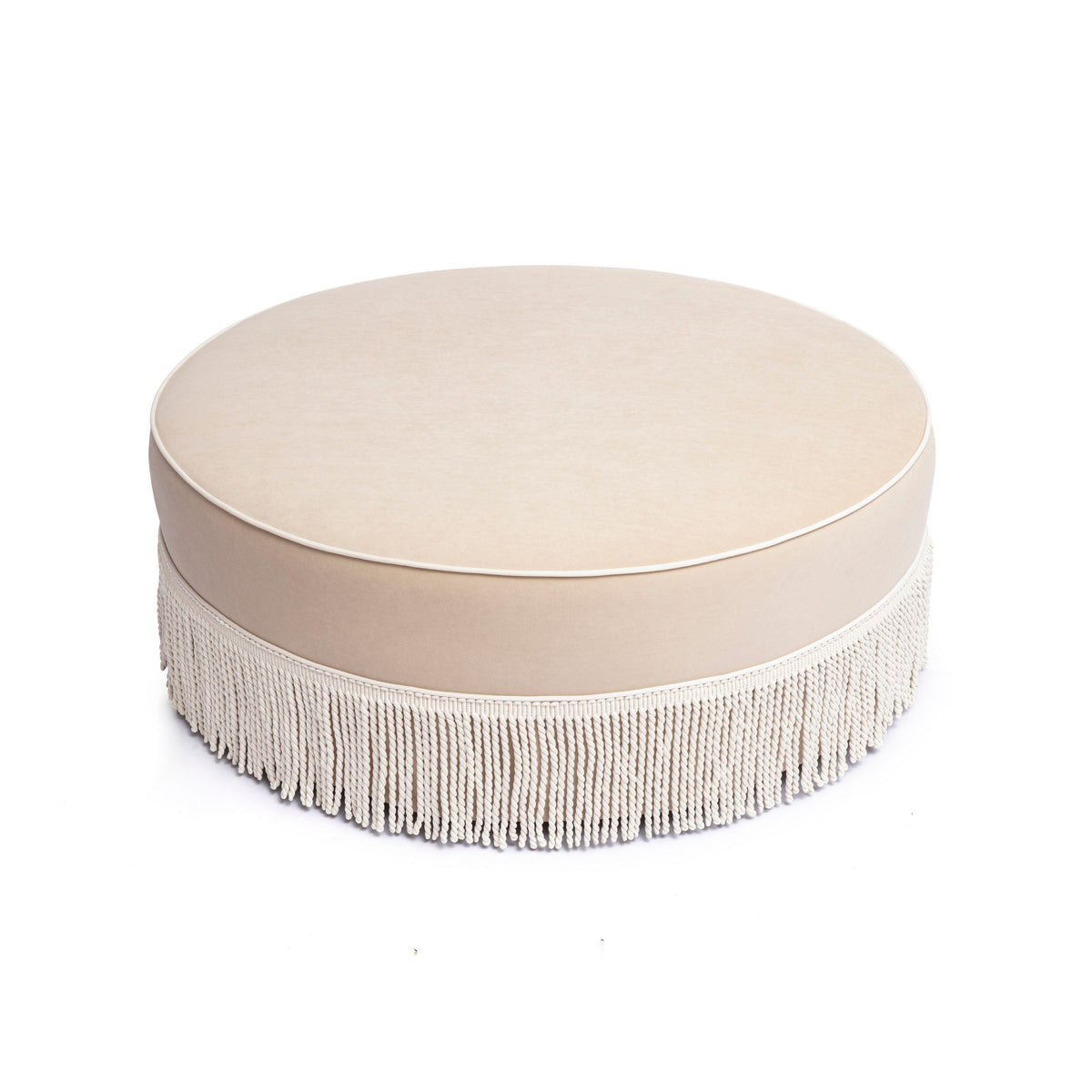 Tan velvet Tassy Round Ottoman styled near an accent armchair in a bedroom