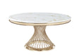 Round white marble dining table with gold veining and a sculptural gold metal base in a contemporary room.
