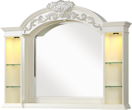 An ornate white arched wall mirror with decorative scrollwork above the mirror and built-in illuminated side shelves with glass display compartments.