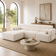 Modern living room with a white sectional sofa, round coffee table, and abstract art on the wall.