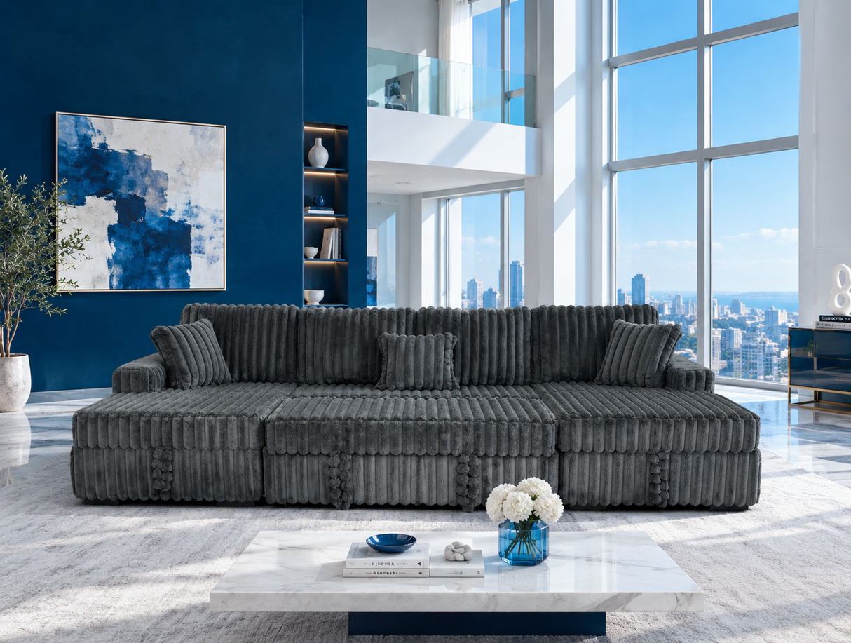 A modern sectional sofa upholstered in dark charcoal gray corduroy fabric, styled in a contemporary high-rise apartment living room with a blue accent wall and large windows.