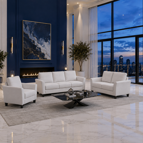 A modern living room set featuring a white three-seat sofa, a matching two-seat loveseat, and a white armchair arranged around a black coffee table on a light gray rug. The room has a deep blue accent wall with a fireplace and large windows overlooking a city skyline at dusk.