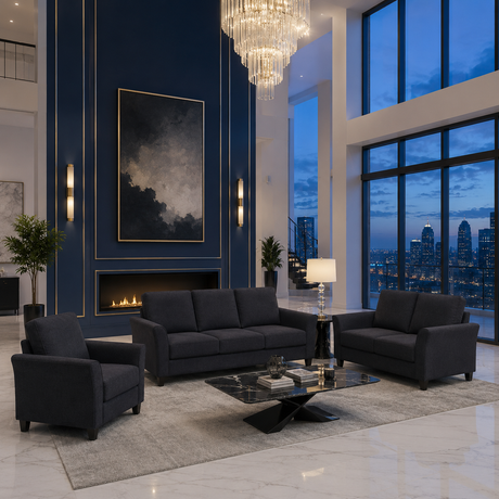 A modern living room set featuring a dark gray three-seater sofa, a matching two-seater armchair, and a small side table with a lamp, arranged on a light gray rug in front of a blue wall with gold trim and a fireplace. Large windows show a city skyline at dusk.