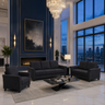 A modern living room set featuring a dark gray three-seater sofa, a matching two-seater armchair, and a small side table with a lamp, arranged on a light gray rug in front of a blue wall with gold trim and a fireplace. Large windows show a city skyline at dusk.