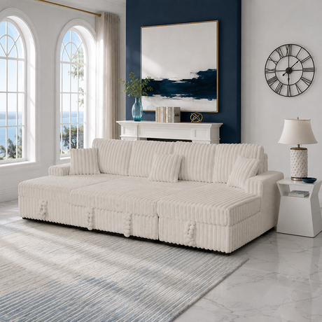 A cream ribbed upholstered sofa with matching throw pillows in a bright, modern living room with arched windows, a blue accent wall, and a white side table.