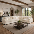 A large cream sectional sofa in a modern, sunlit living room with wood ceiling beams, a dark wood coffee table, and a textured beige rug.