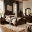 A classic dark wood bed with an ornate carved headboard and footboard, styled in a cozy bedroom with beige and gray bedding, a matching dark wood nightstand, dresser, and mirror.