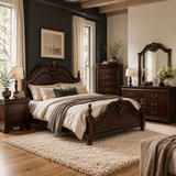 A classic dark wood bed with an ornate carved headboard and footboard, styled in a cozy bedroom with beige and gray bedding, a matching dark wood nightstand, dresser, and mirror.