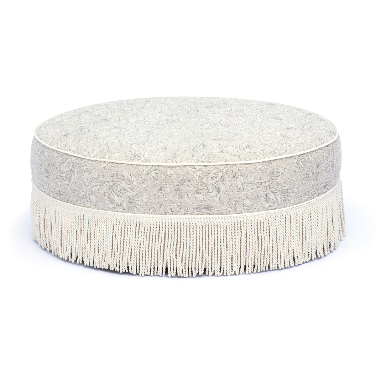 Low angle perspective of Tassy Tasseled Round Ottoman displaying full perimeter fringe