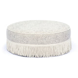 Low angle perspective of Tassy Tasseled Round Ottoman displaying full perimeter fringe