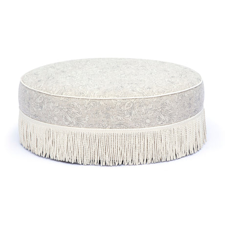 Low angle perspective of Tassy Tasseled Round Ottoman displaying full perimeter fringe