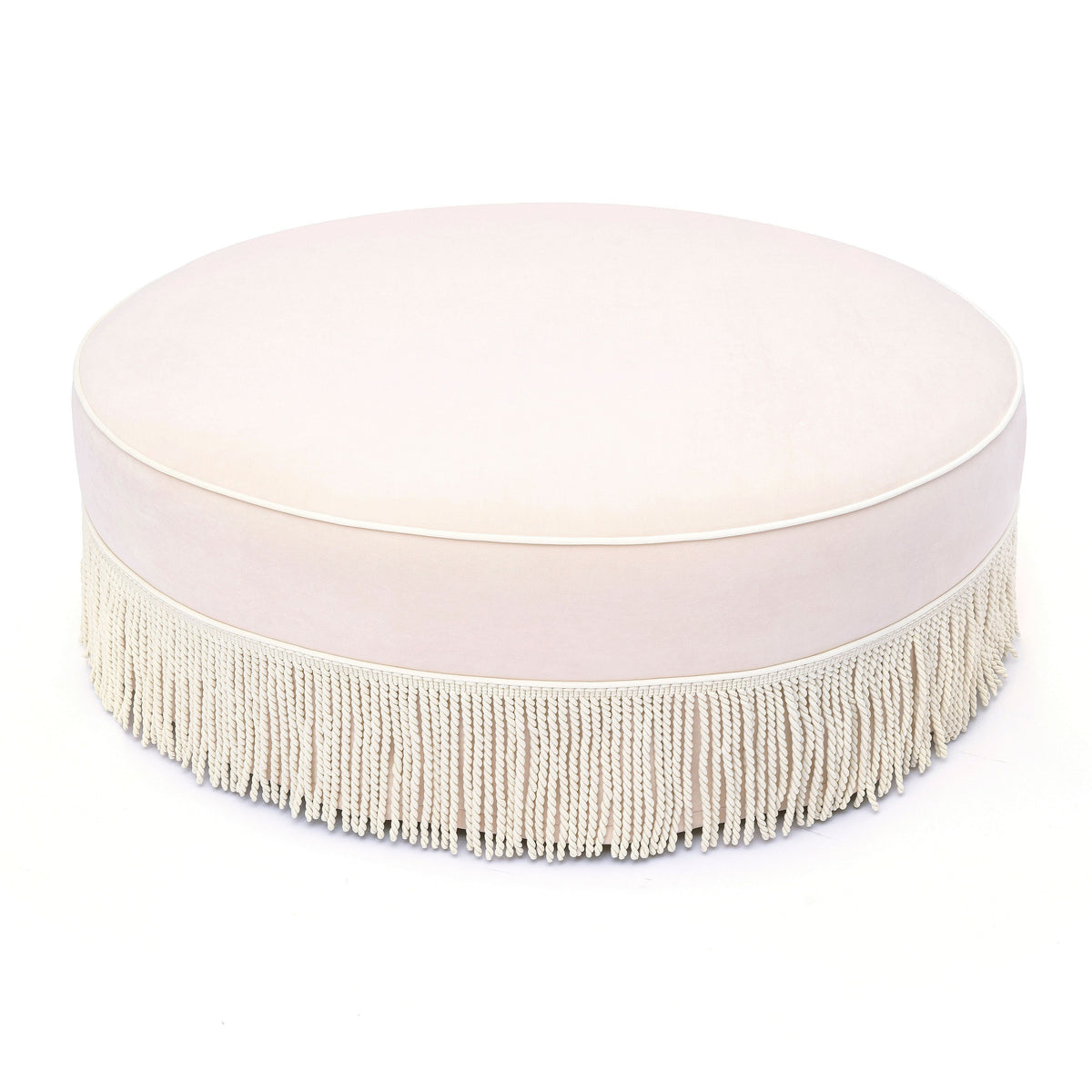 Close-up detail of pink velvet upholstery and tailored fringe on Tassy Round Ottoman