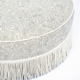 Tassy Tasseled Round Ottoman styled beside coffee table in contemporary seating area