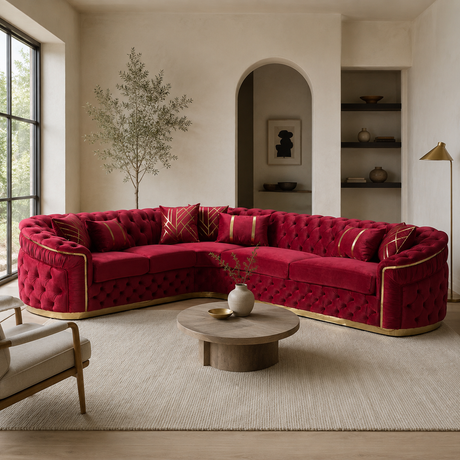 A luxurious curved tufted sofa upholstered in rich red velvet with gold trim, styled in a modern, warm-toned living room with a round wooden coffee table and neutral walls.