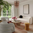 Modern living room with white furniture, a tree, and decorative elements.